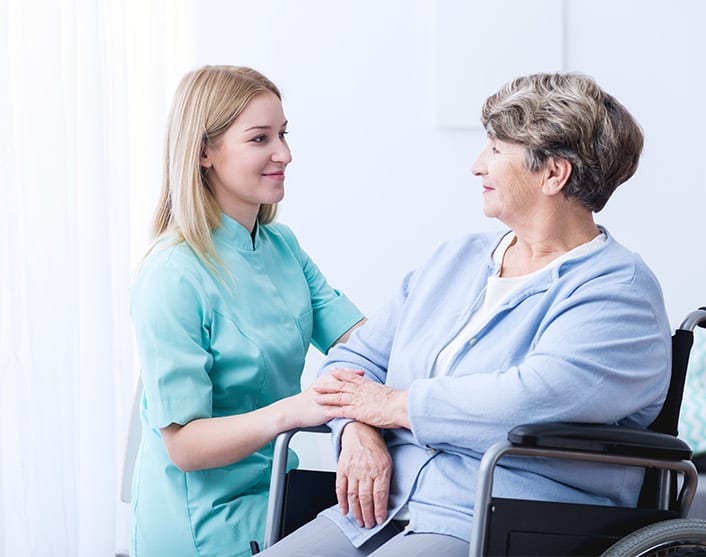 Image of a healthcare worker engaged with a patient in a wheelchair