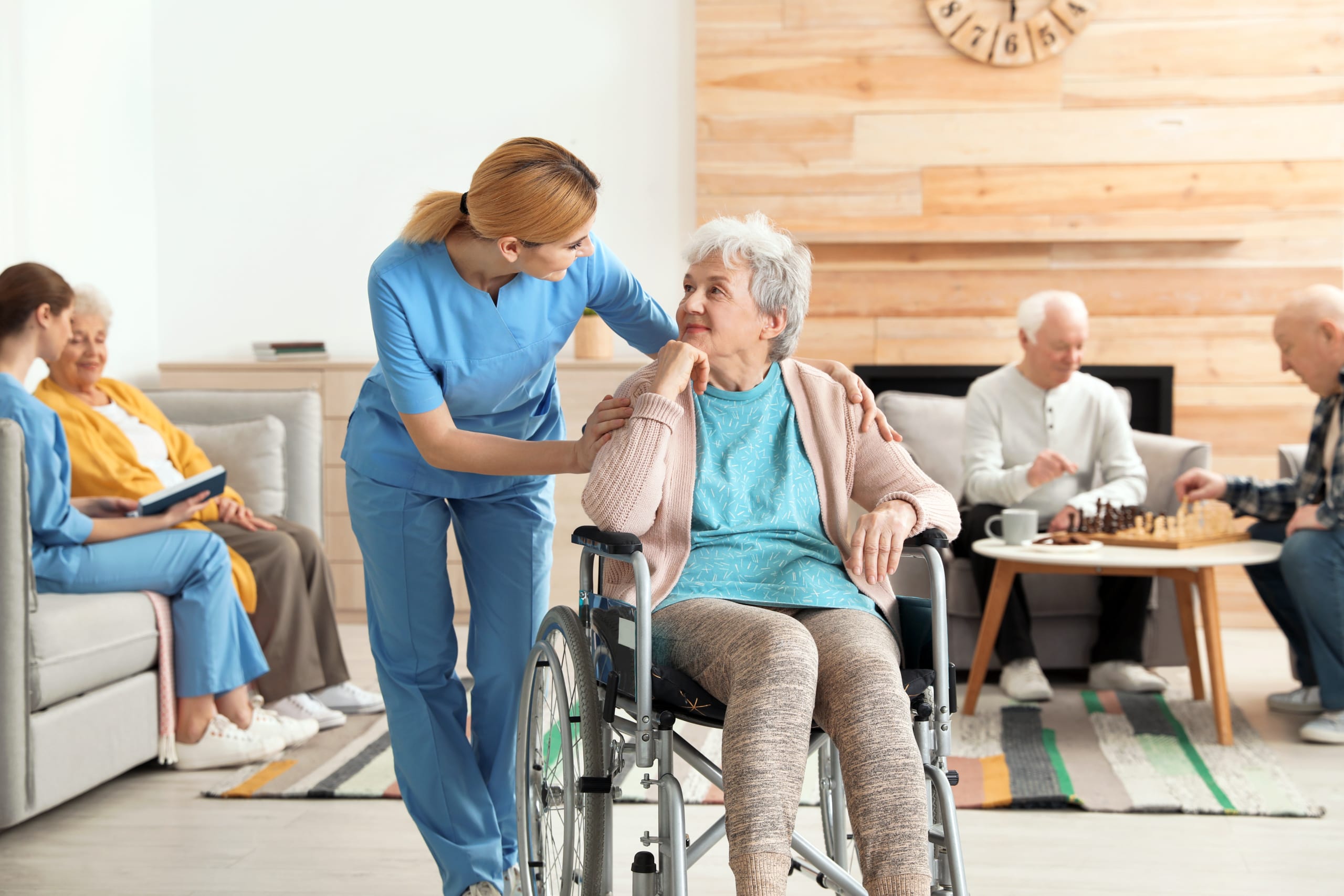 A woman in scrubs interacting with a nursing home patient